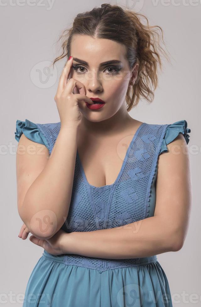 beautiful woman in blue dress posing in studio on gray background photo