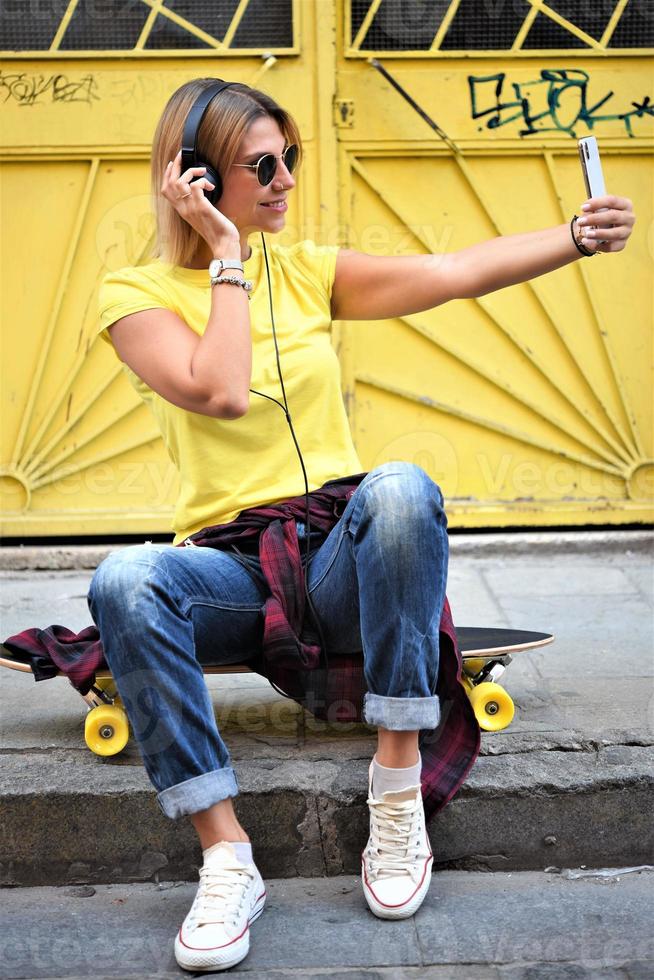 Beautiful hipster girl with skate board wearing sunglasses in the city. photo