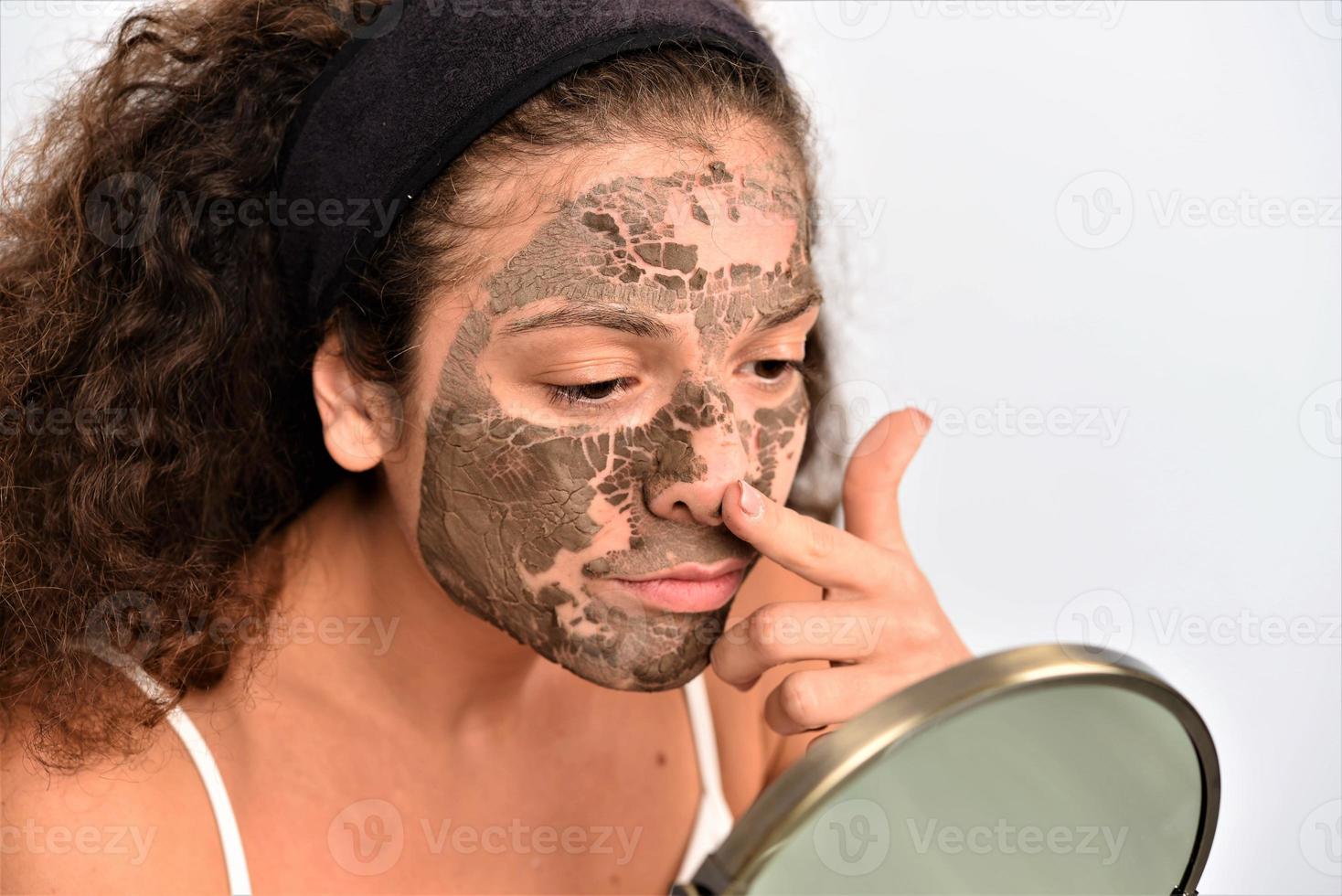bella mujer quitándose la máscara facial de arcilla de la cara foto