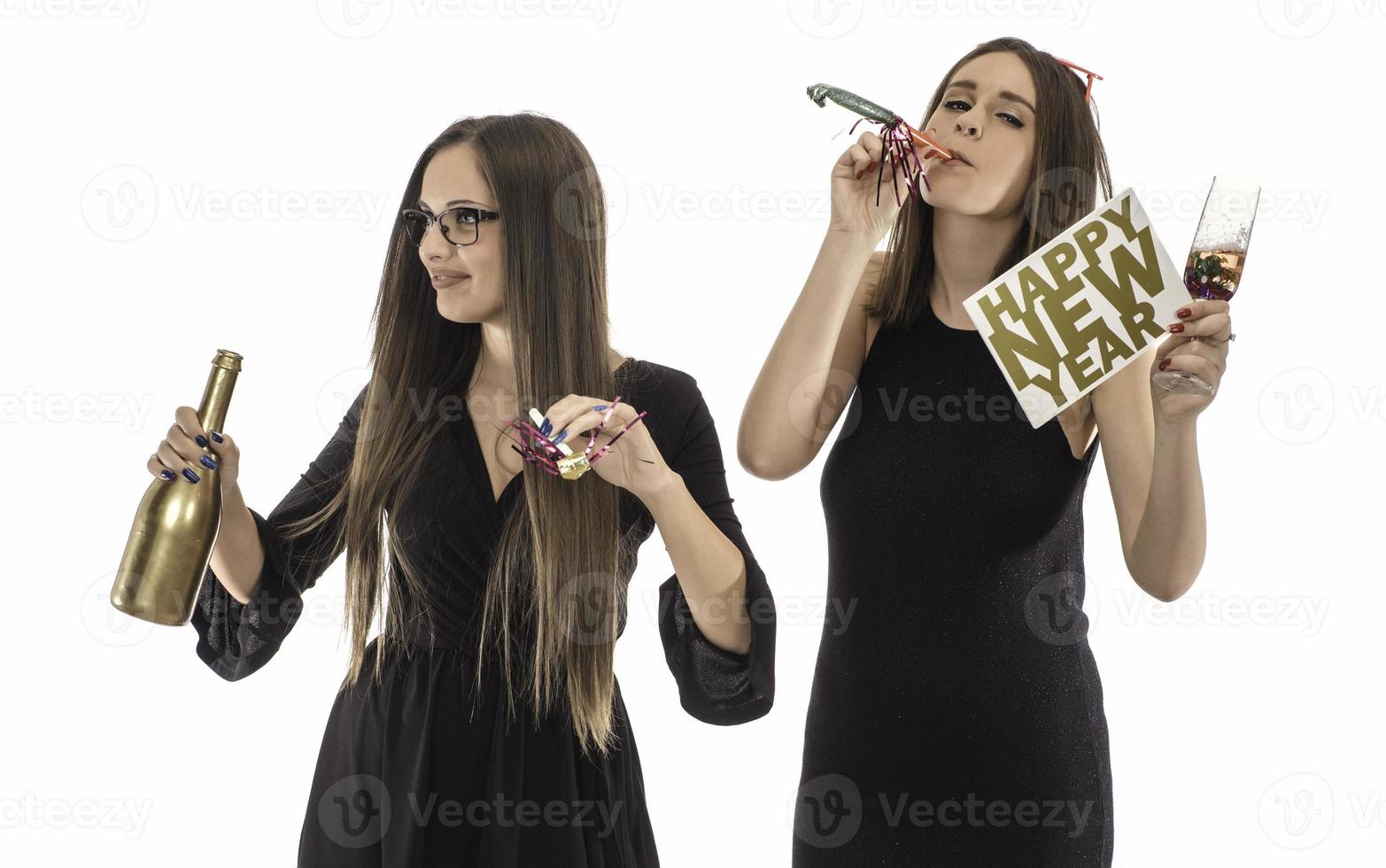 Two female friends celebrating New Year with confetti and champagne holding sign. isolated photo