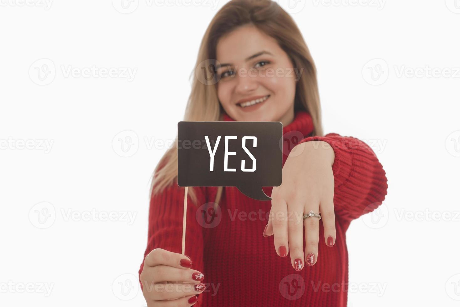 Woman holding engagement ring and sign saying YES photo