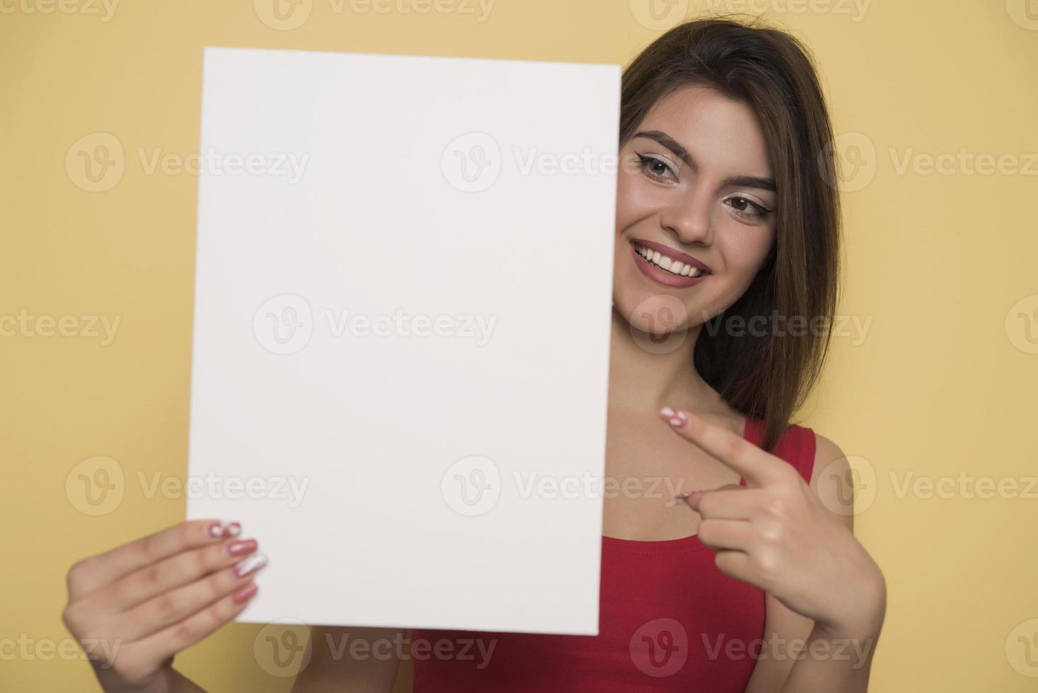 young smiling woman holding a blank sheet of paper for advertising photo