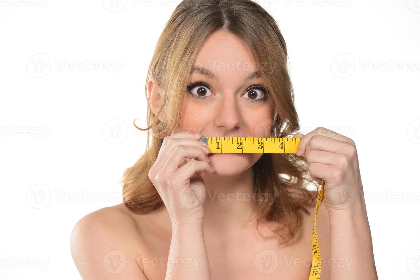 retrato de mujer hermosa con cabello rubio sosteniendo cinta dosificadora sobre fondo blanco foto