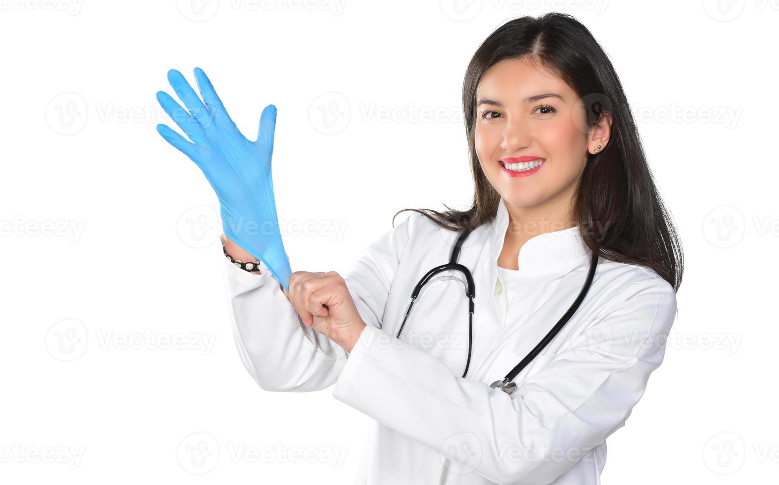A young woman doctor with stethoscope putting a medical gloves, isolated on white background photo