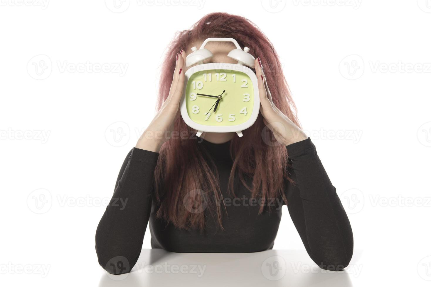 worried young woman holding alarm clock in her hand photo