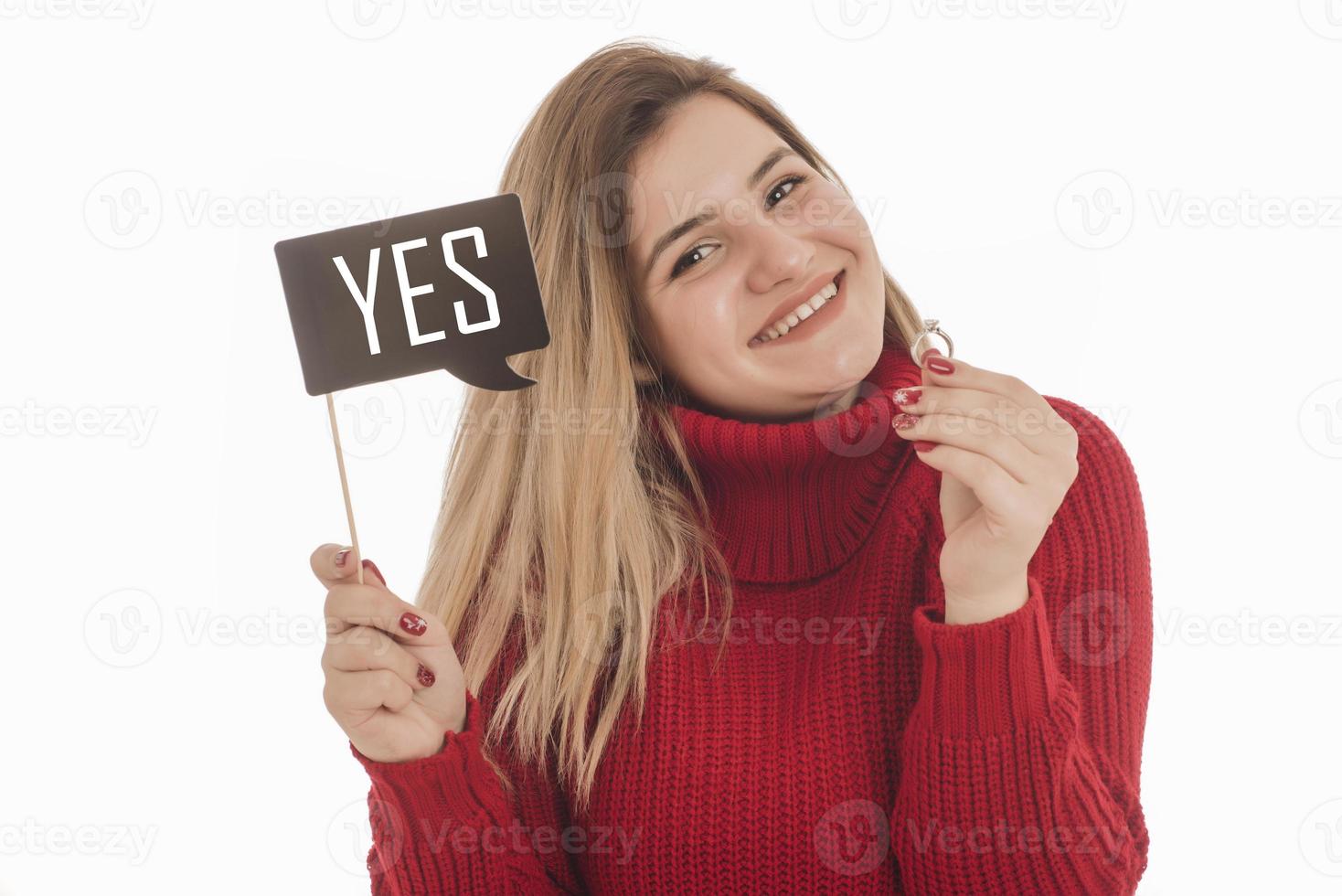 Woman holding engagement ring and sign saying YES photo