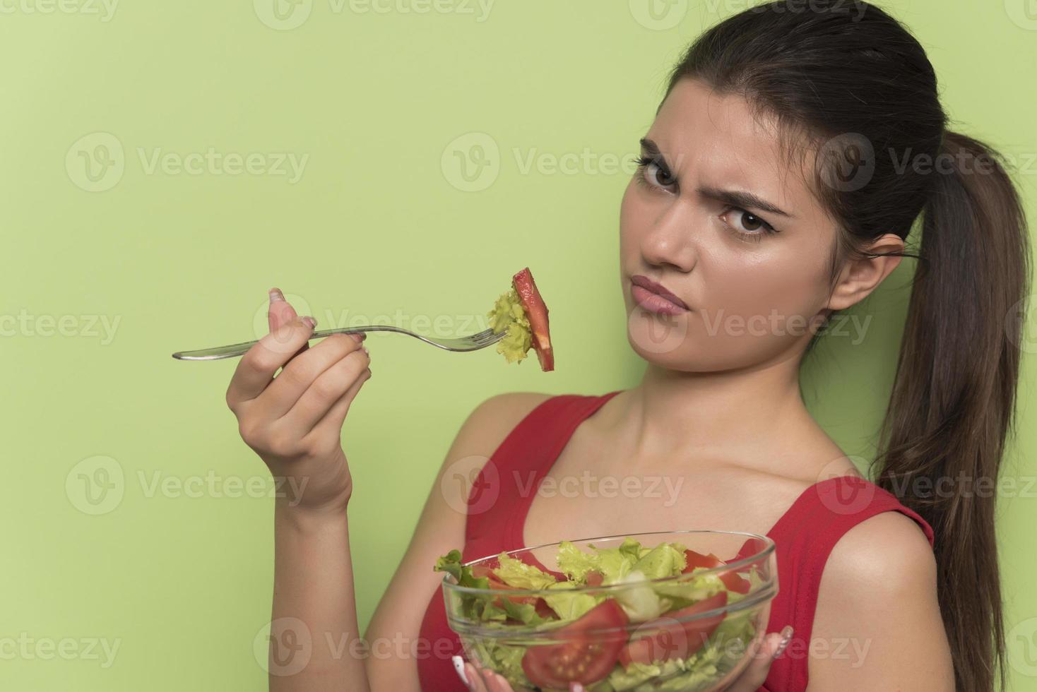 Portrait of a happy playful girl eating fresh salad from a bow photo