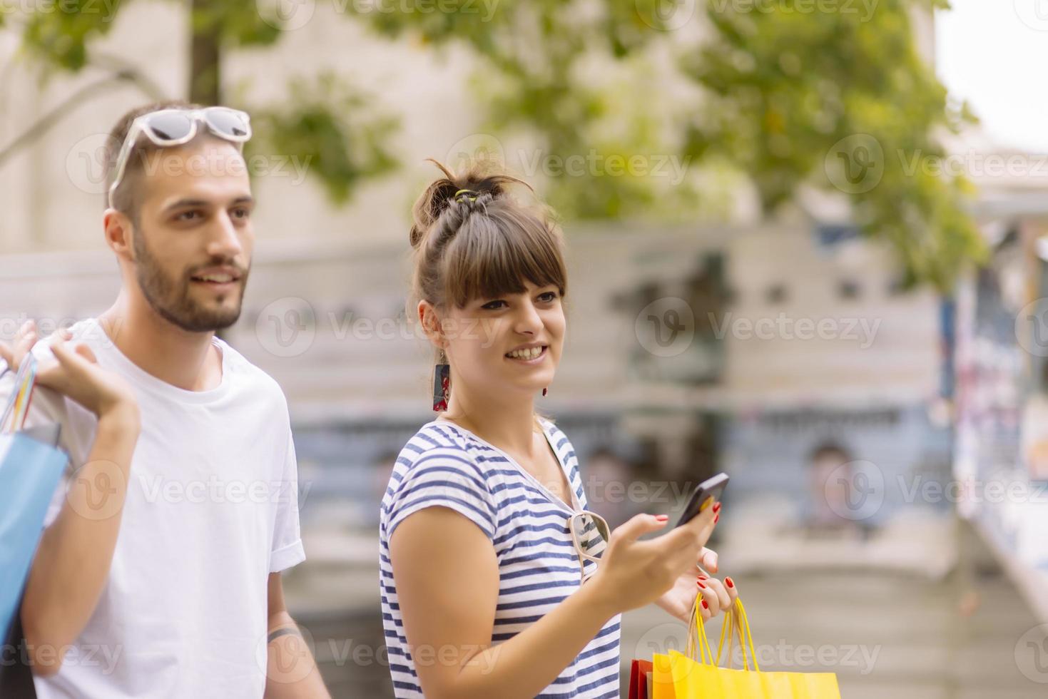 Portrait of cheerful Caucasian young couple man and woman holding many paper bags after shopping while walking and talking on street. Happy family couple with packages outdoor. Buying concept photo