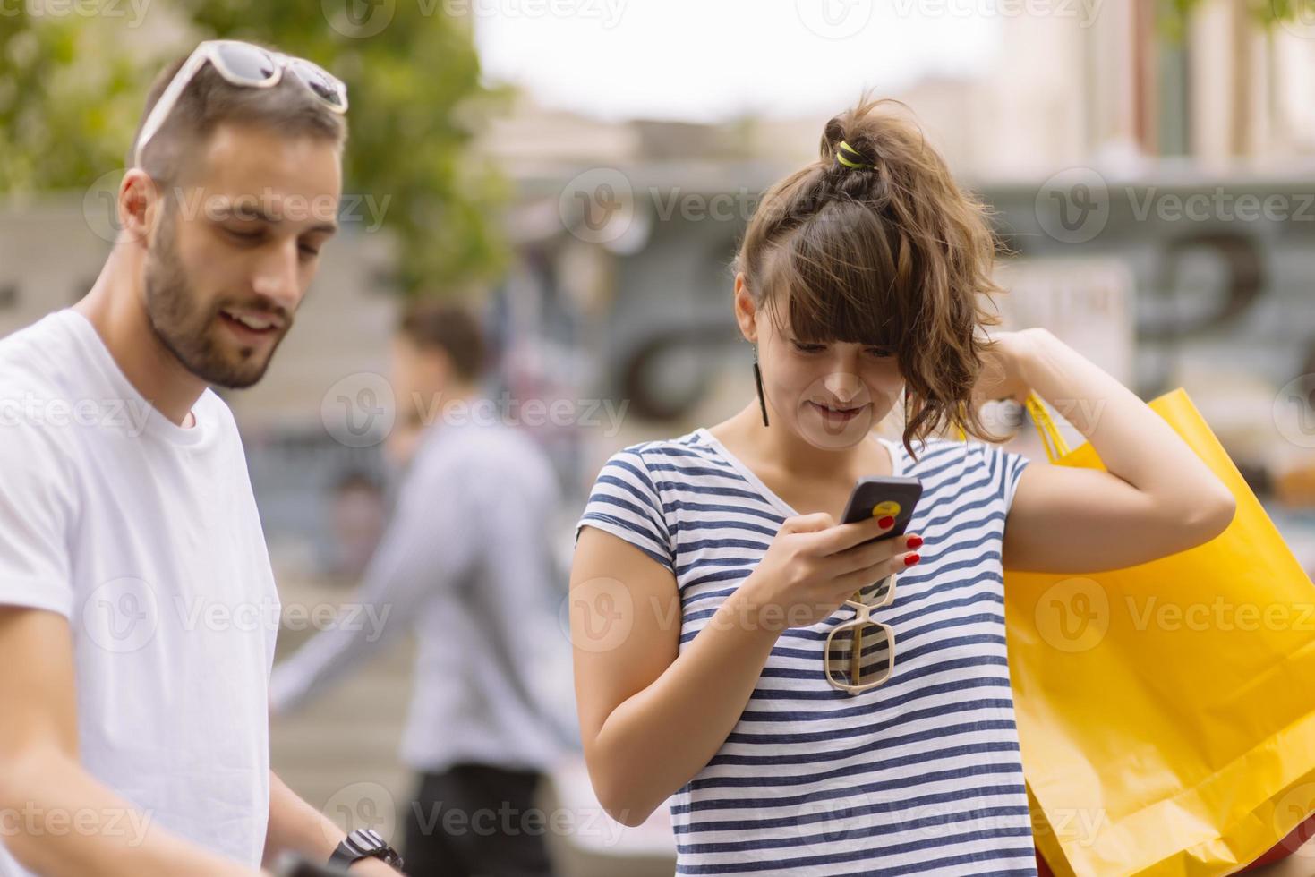 retrato de una alegre pareja joven caucásica hombre y mujer sosteniendo muchas bolsas de papel después de ir de compras mientras camina y habla en la calle. feliz pareja familiar con paquetes al aire libre. concepto de compra foto