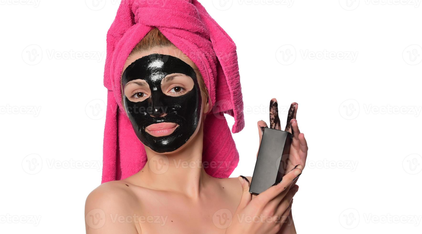 mujer hermosa joven con una máscara para la cara del barro negro terapéutico foto