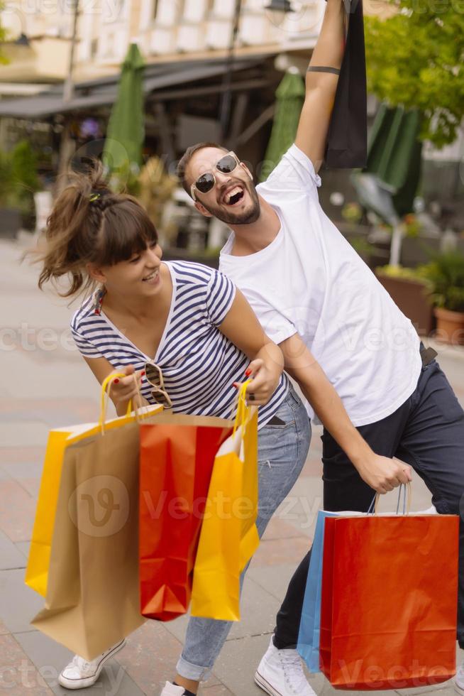 Portrait of cheerful Caucasian young couple man and woman holding many paper bags after shopping while walking and talking on street. Happy family couple with packages outdoor. Buying concept photo