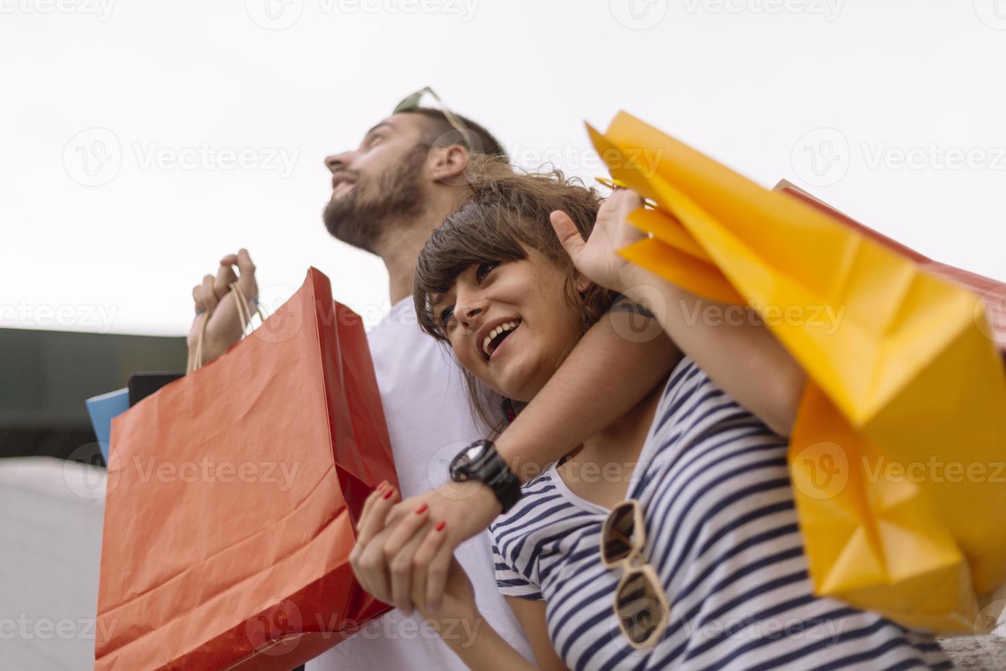 Portrait of cheerful Caucasian young couple man and woman holding many paper bags after shopping while walking and talking on street. Happy family couple with packages outdoor. Buying concept photo
