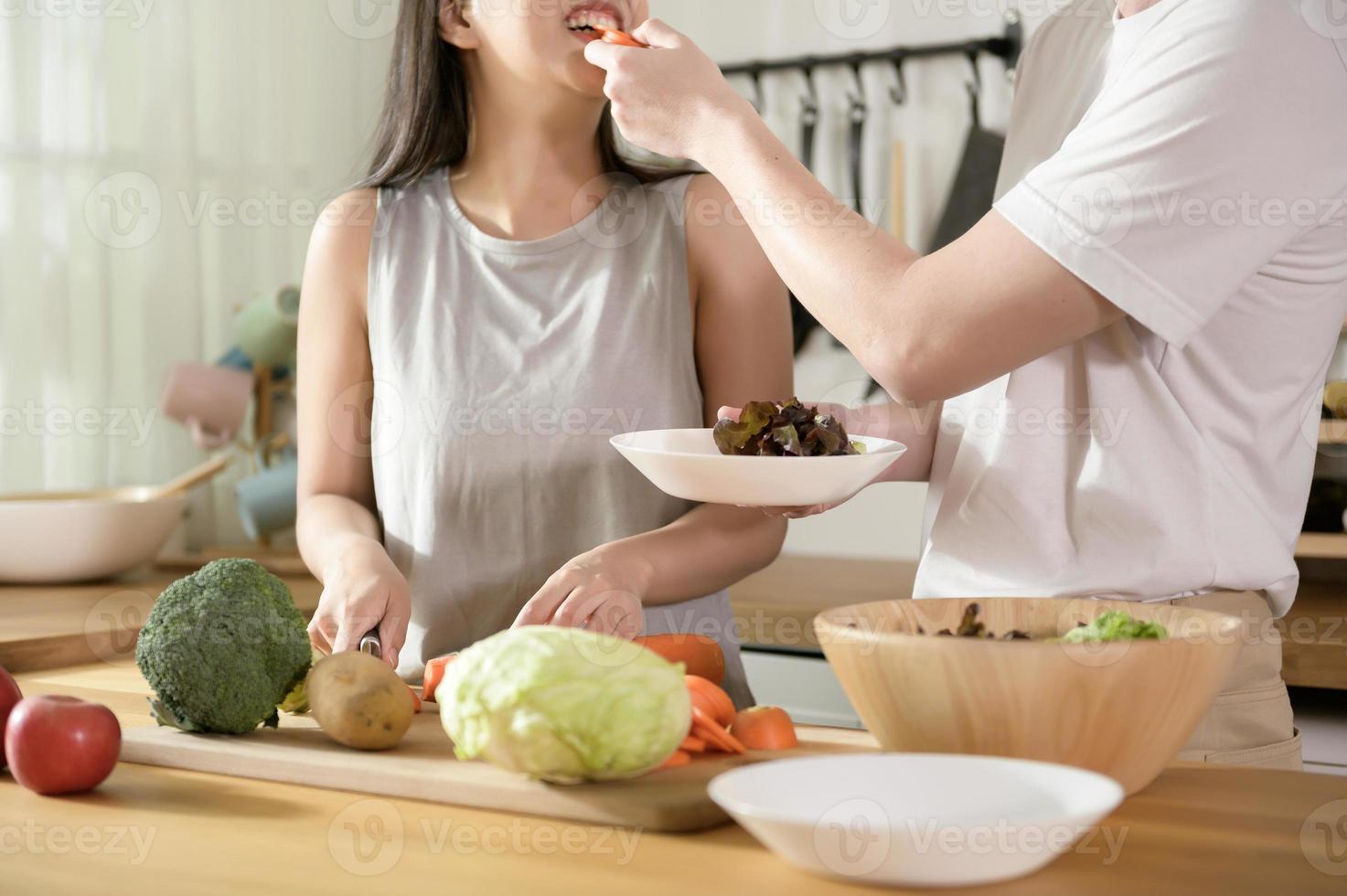 An Asian young couple enjoy cooking with healthy vegetables and fruits ingredients in kitchen at home , healthy wellness lifestyle concept. photo