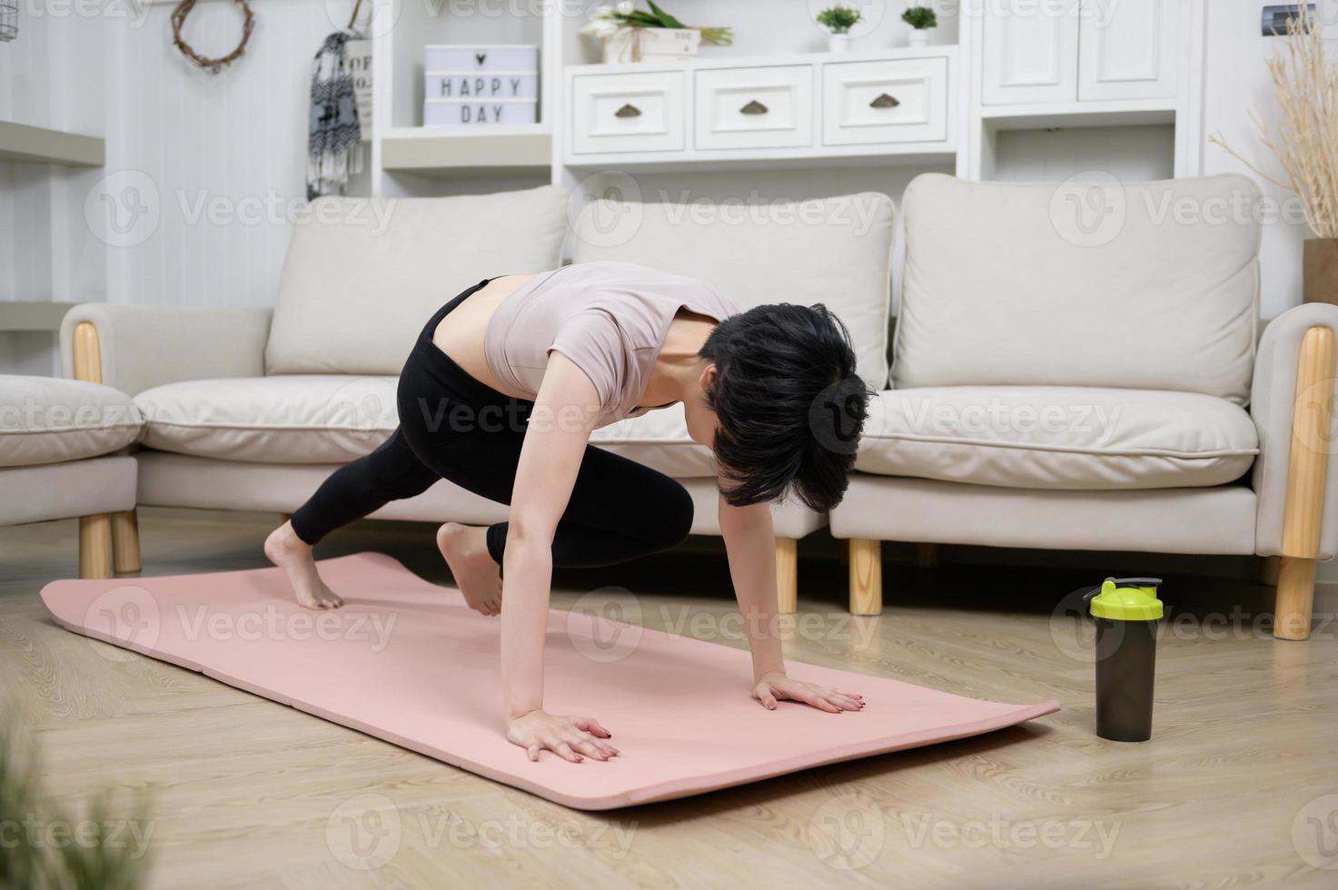 una joven asiática hace ejercicio en una alfombra de fitness, hace ejercicio en casa, un concepto de estilo de vida saludable foto