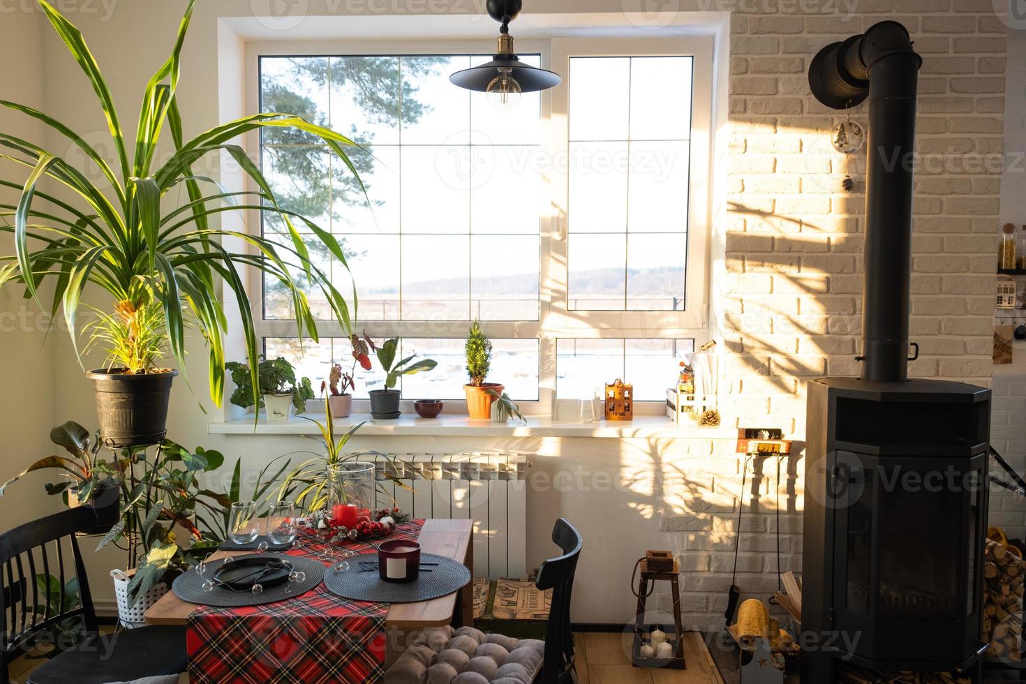 Sunny interior of a loft-style house with potted plants, a large window, a covered table for the Christmas and New Year holidays photo