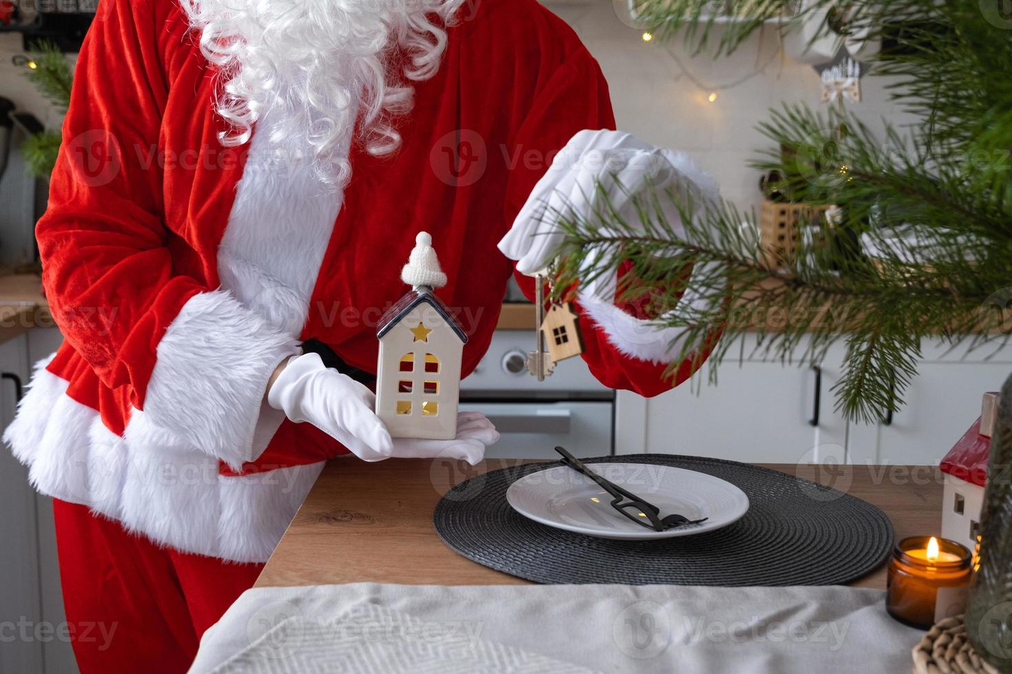 House key with keychain cottage in hands of Santa Claus outdoor in snow. Deal for real estate, purchase, construction, relocation, mortgage. Cozy home. Merry Christmas, new year booking event and hall photo