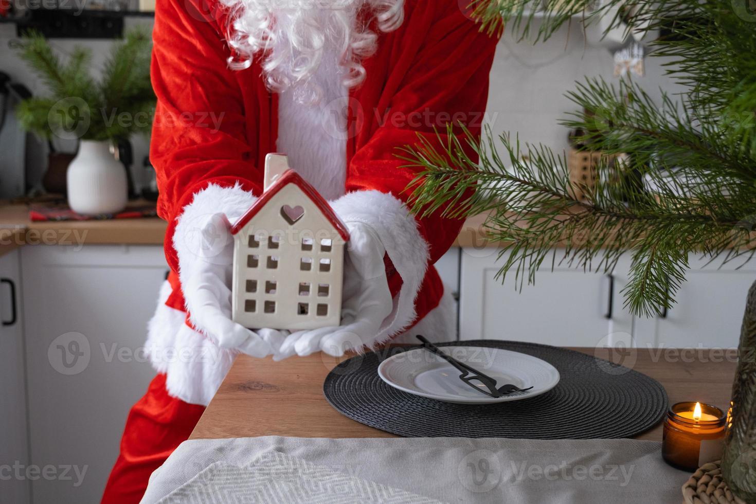 House key with keychain cottage in hands of Santa Claus outdoor in snow. Deal for real estate, purchase, construction, relocation, mortgage. Cozy home. Merry Christmas, new year booking event and hall photo