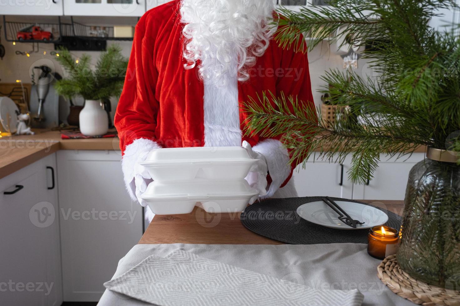 Food delivery to home service containers in hands of Santa Claus puts it on kitchen table and takes it away. Ready-made hot order, Christmas, New year holidays catering. photo