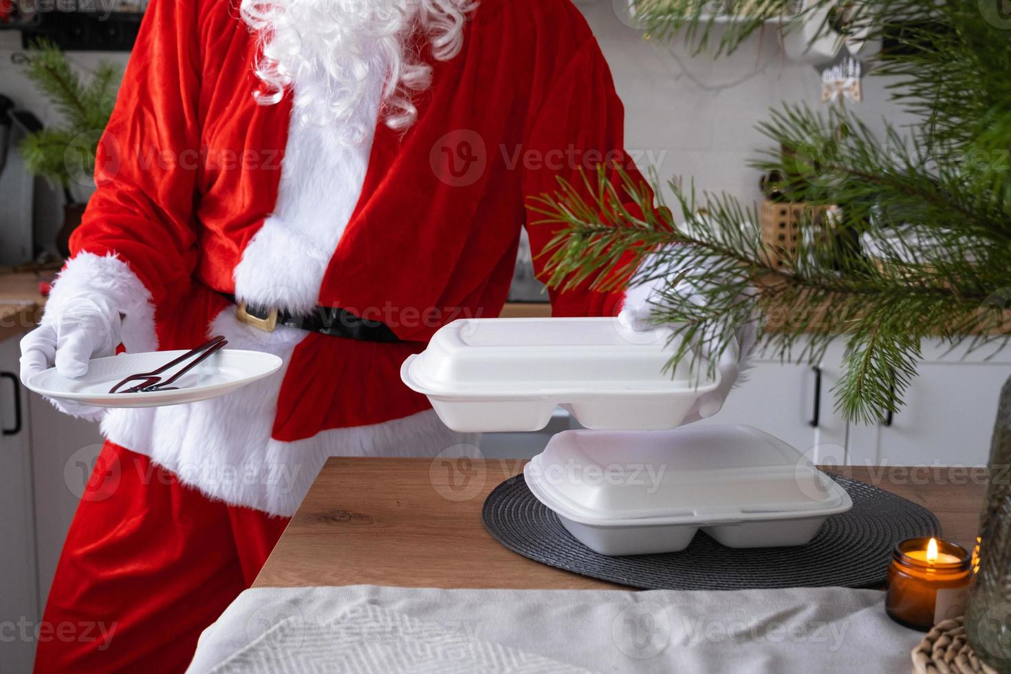 Food delivery to home service containers in hands of Santa Claus puts it on kitchen table and takes it away. Ready-made hot order, Christmas, New year holidays catering. photo