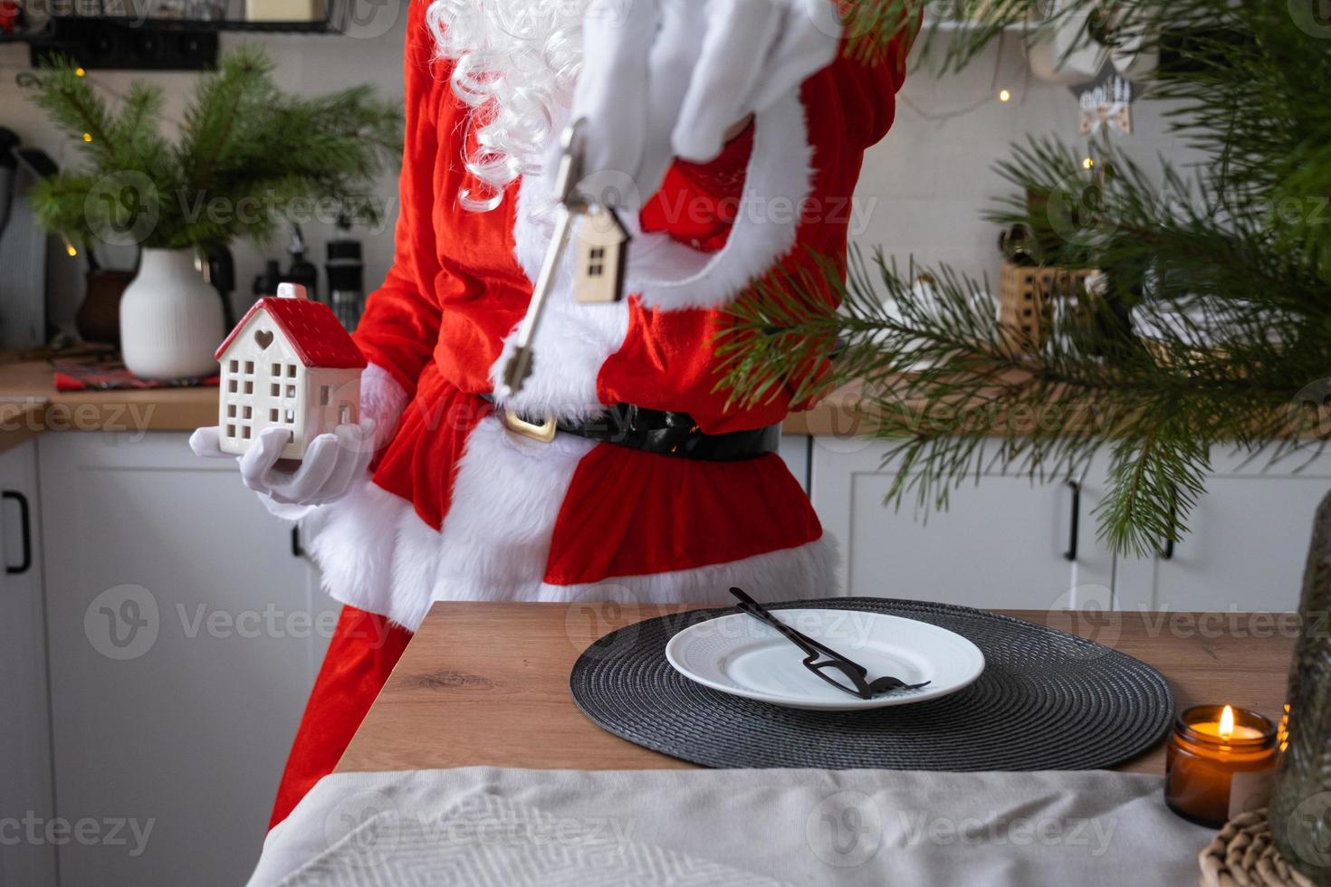 House key with keychain cottage in hands of Santa Claus outdoor in snow. Deal for real estate, purchase, construction, relocation, mortgage. Cozy home. Merry Christmas, new year booking event and hall photo