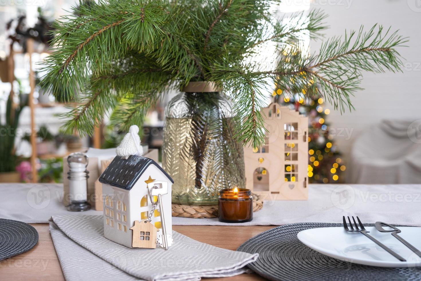 Key to the house on cozy home with Christmas decor on table of festive kitchen. Gift for New Year. Building, design, project, moving to new house, mortgage, rent and purchase real estate photo