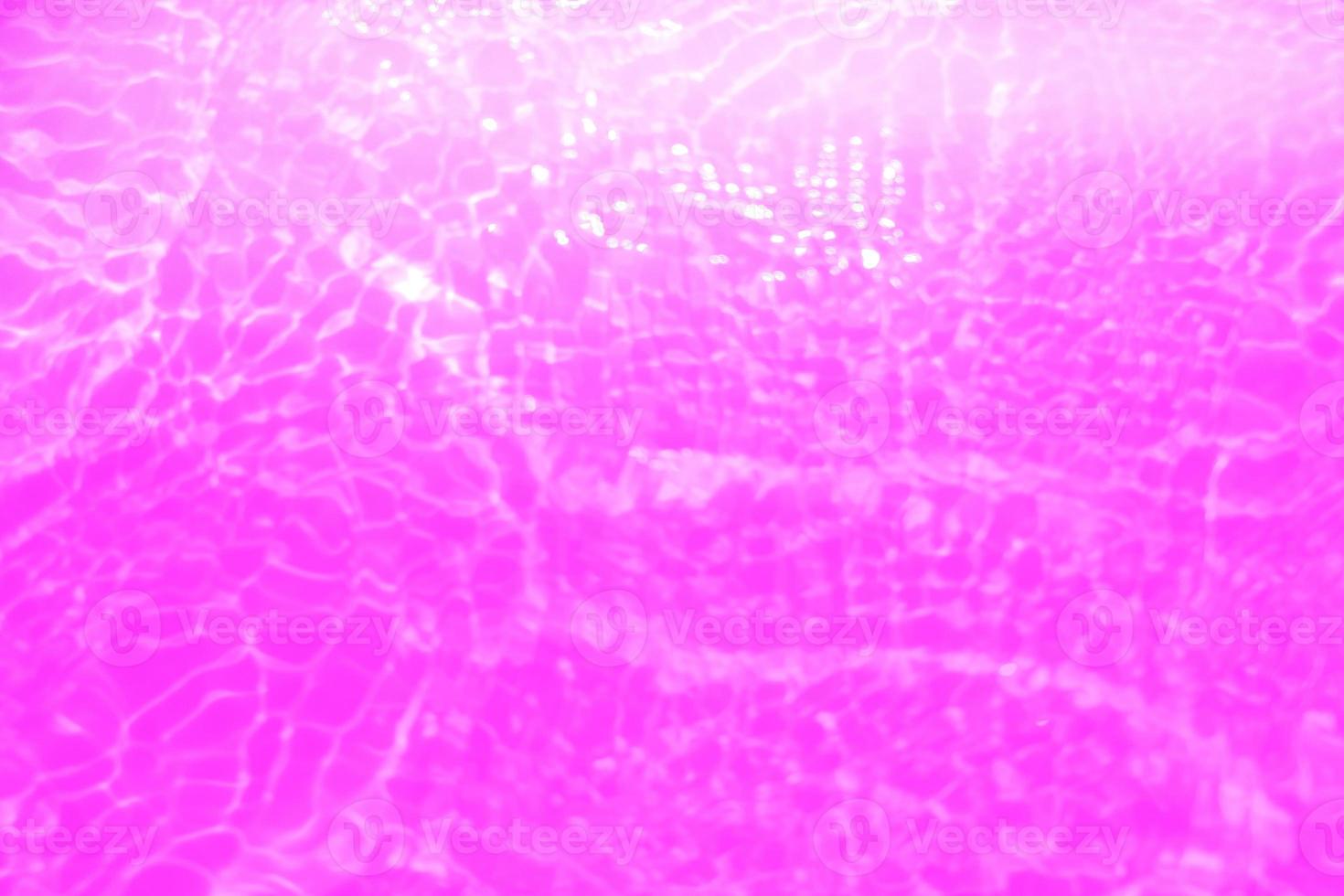 Defocus blurred transparent purple colored clear calm water surface texture with splashes and bubbles. Trendy abstract nature background. Water waves in sunlight with copy space. Pink water drop shine photo