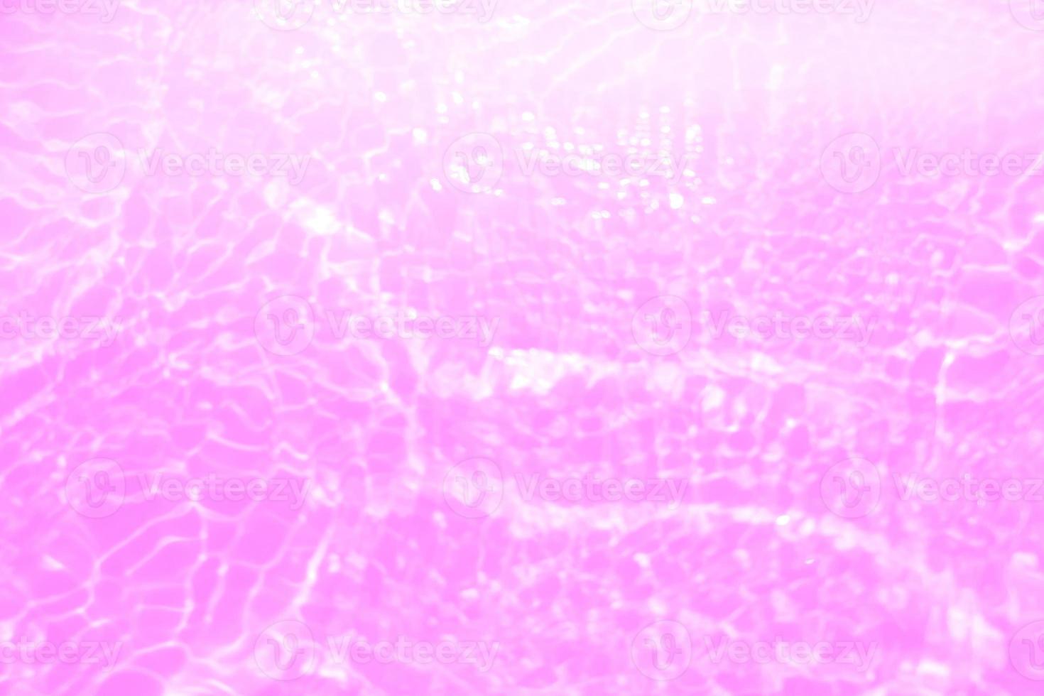 Defocus blurred transparent purple colored clear calm water surface texture with splashes and bubbles. Trendy abstract nature background. Water waves in sunlight with copy space. Pink water drop shine photo