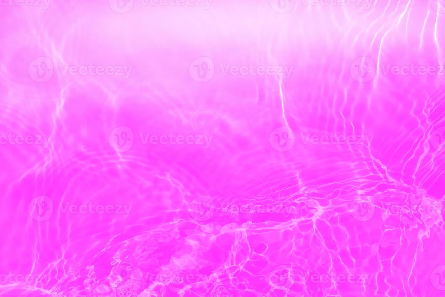 Defocus blurred transparent purple colored clear calm water surface texture with splashes and bubbles. Trendy abstract nature background. Water waves in sunlight with copy space. Pink water drop shine photo