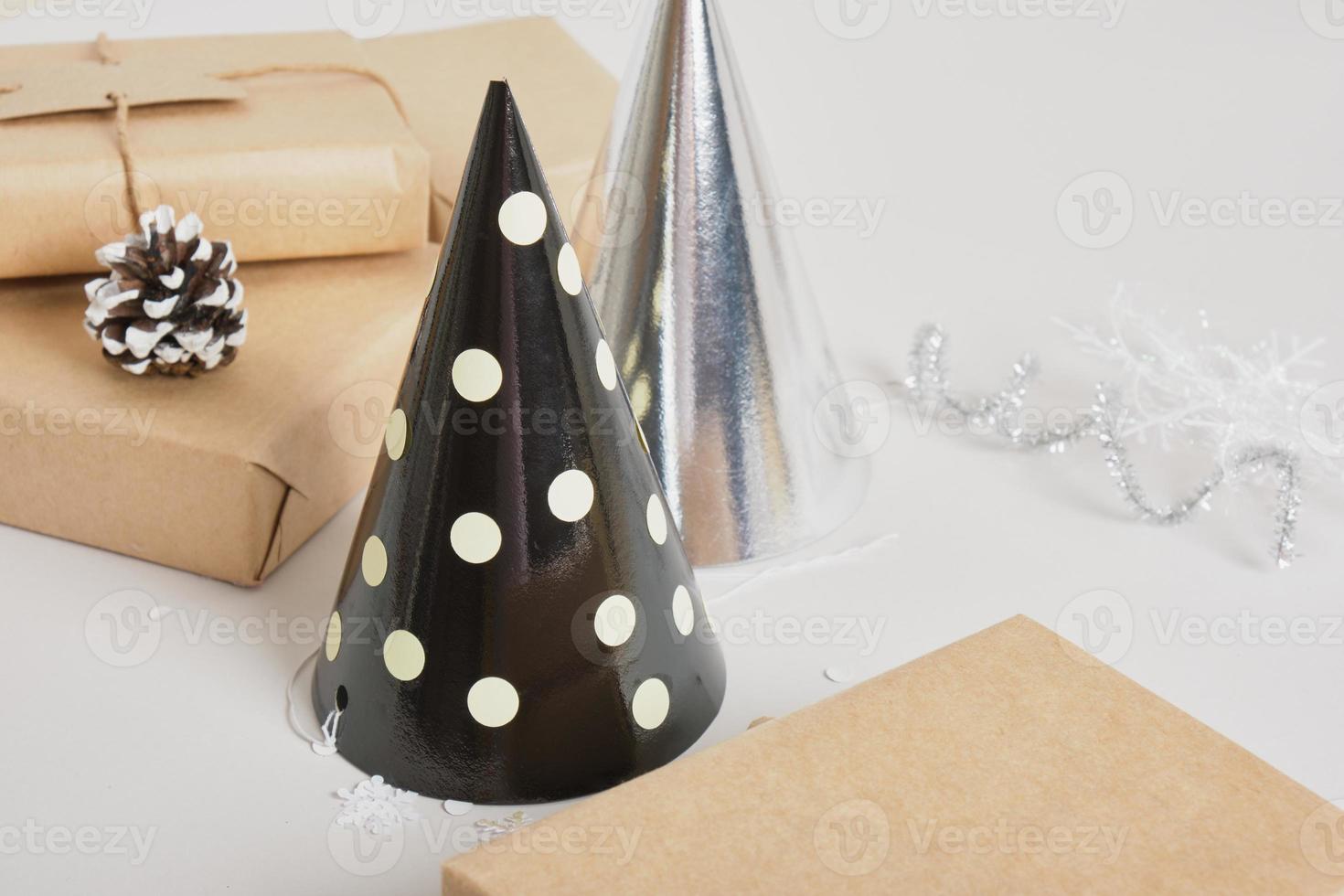 party hats and gifts boxes on gray background, shiny festive new year or christmas decor, photo