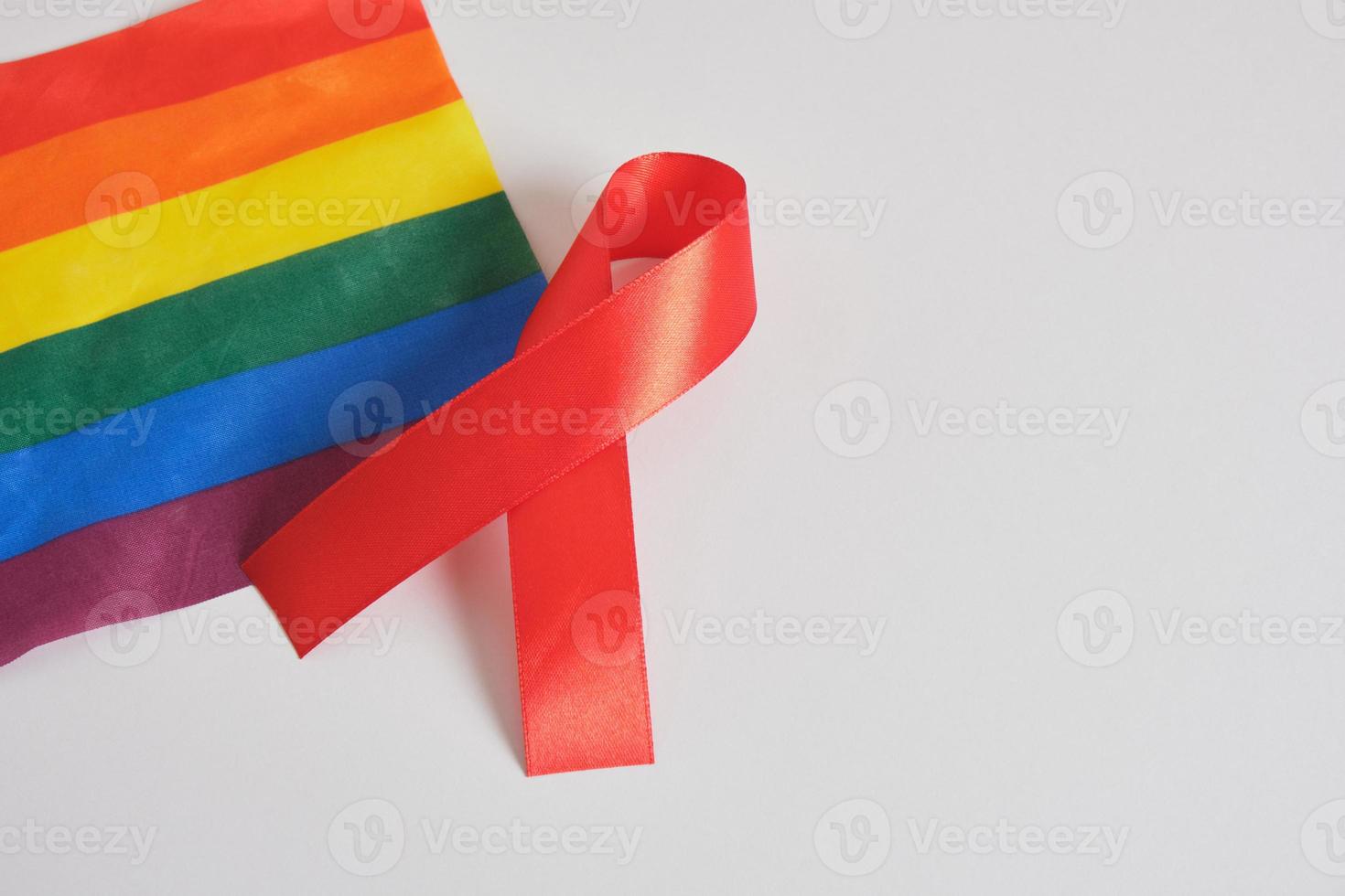 Stop AIDS, HIV concept. Red ribbon against on flag of LGBT pride photo