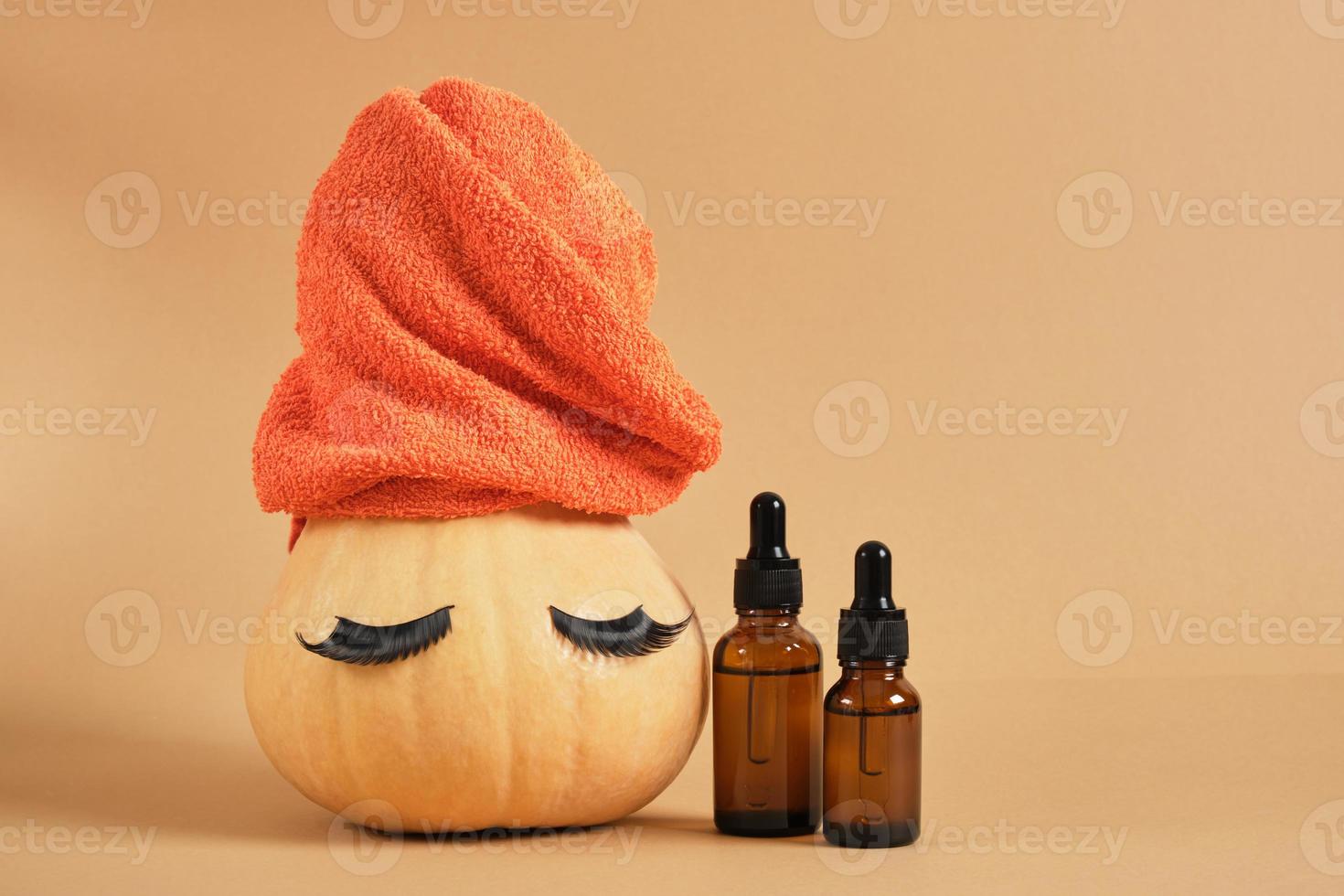 mock up set of cosmetic containers and pumpkin with towel and false eyelashes on beige background photo