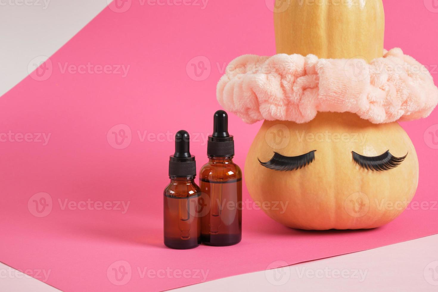 mock up set of cosmetic containers and pumpkin with headband and false eyelashes on pink background photo