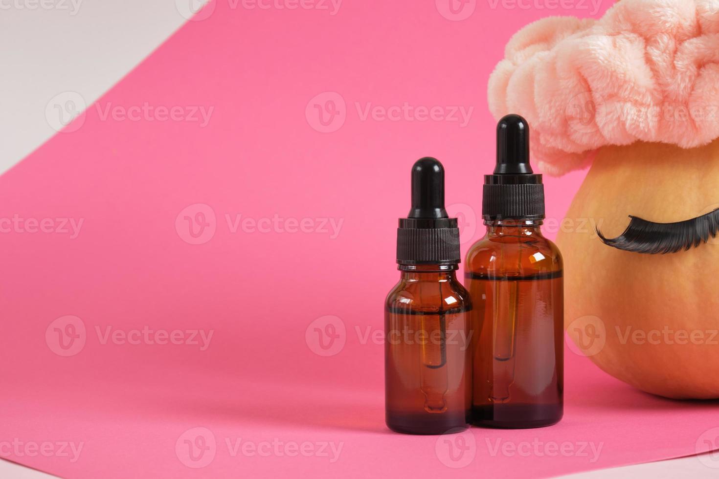mock up set of cosmetic containers and pumpkin with headband and false eyelashes on pink background photo