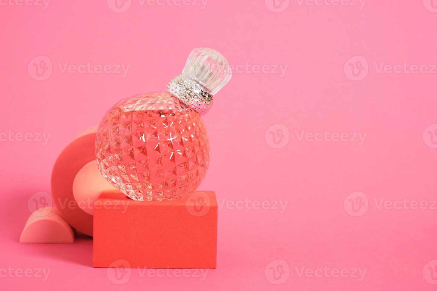 cristal glass perfume bottle on pink background copy space photo