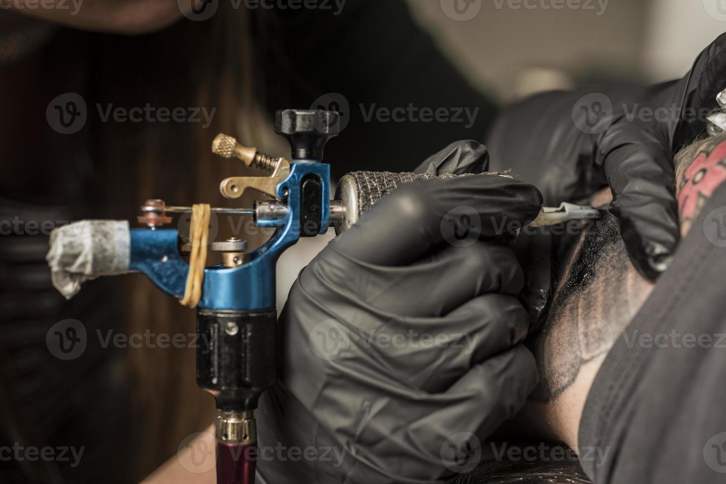 máquina de tatuaje de cerca. mujer creando una imagen a mano con ella en el salón foto