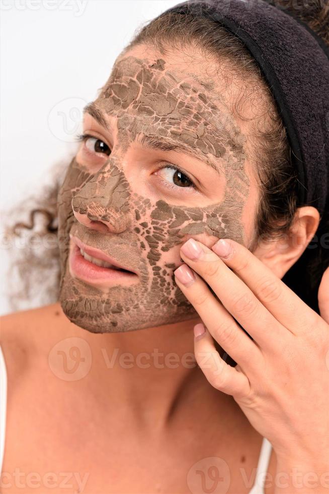 Beautiful woman having clay facial mask photo