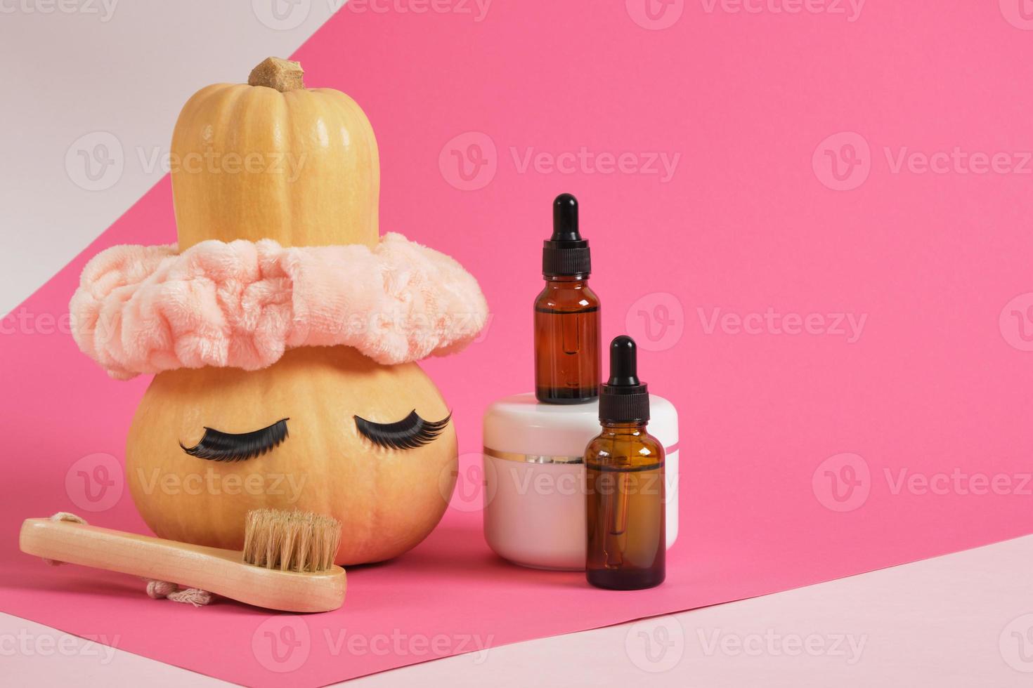 mock up set of cosmetic containers and pumpkin with headband and false eyelashes on pink background photo