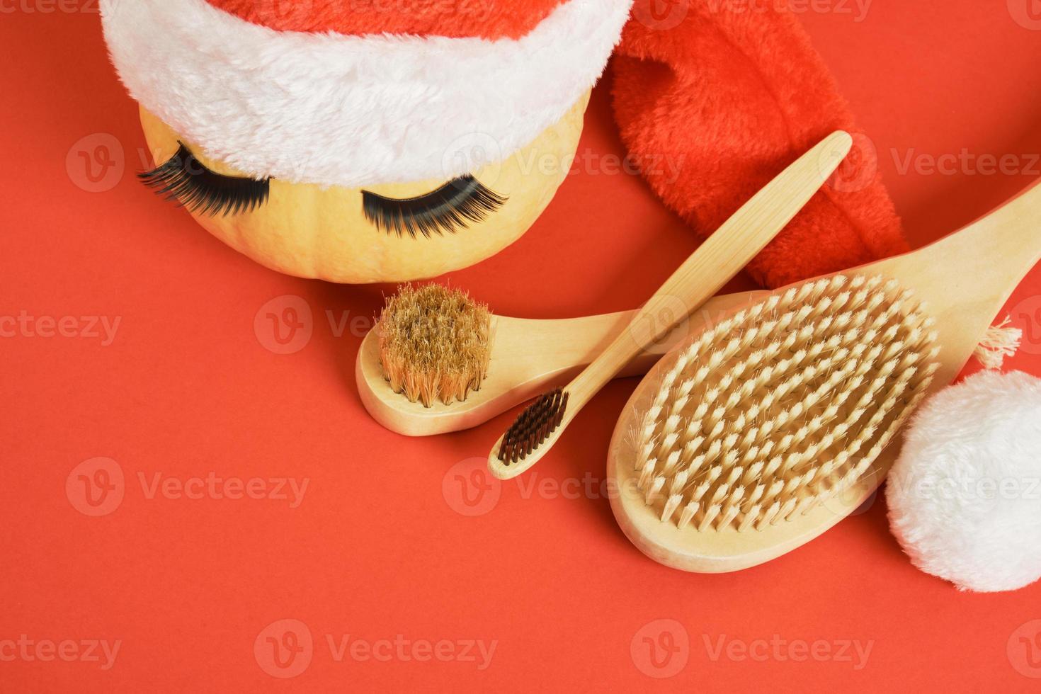 bamboo toothbrush, wooden massage brushes, pumpkin with false eyelashes and towel on gray background photo