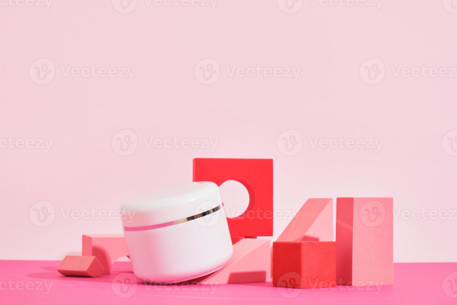 tarro blanco de crema sobre un podio rosa sobre un fondo rosa, botellas para perfume o suero foto