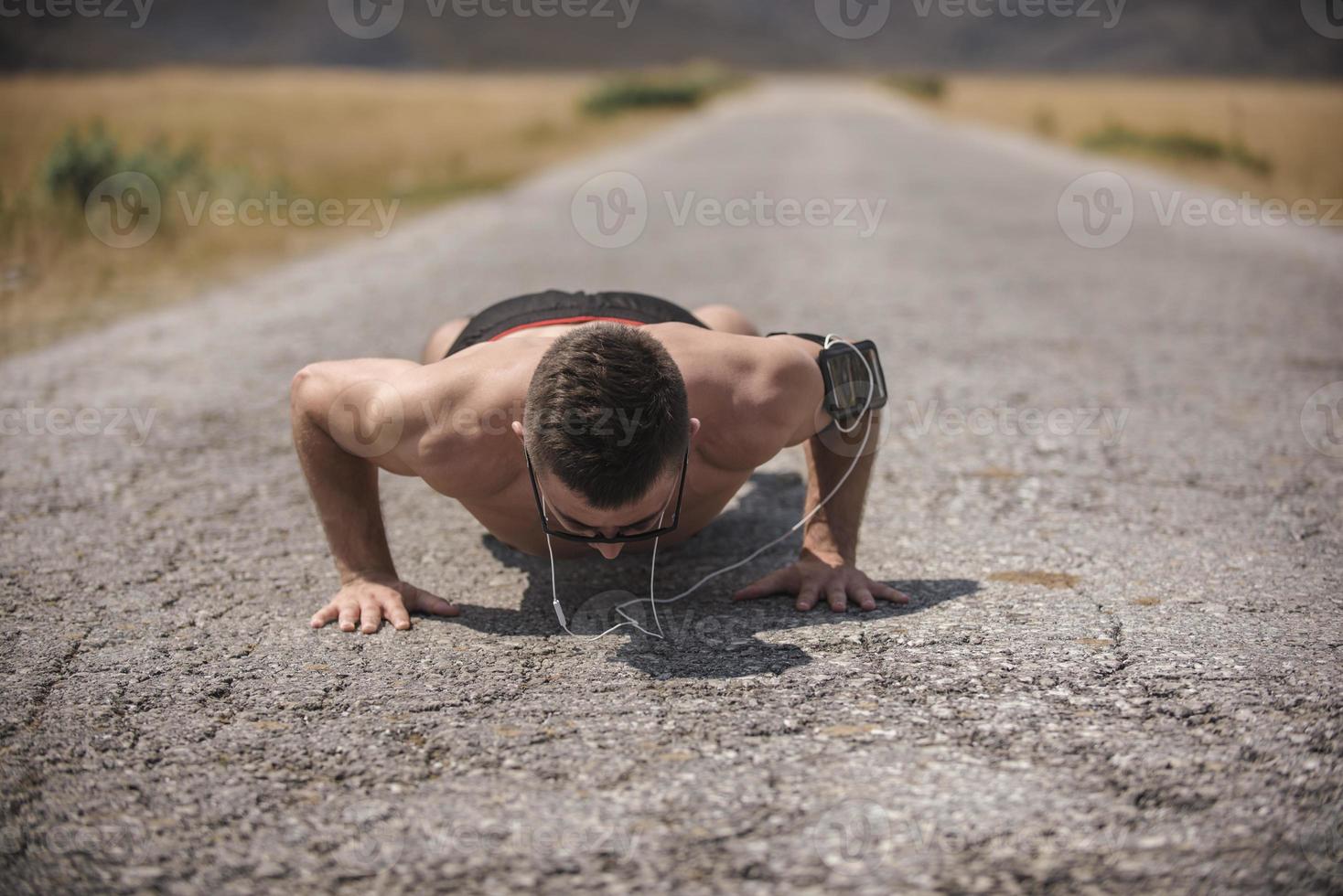 Male athlete exercising push up outside in sunny sunshine. Fit shirtless male fitness model in crossfit exercise outdoors. Healthy lifestyle concept. photo