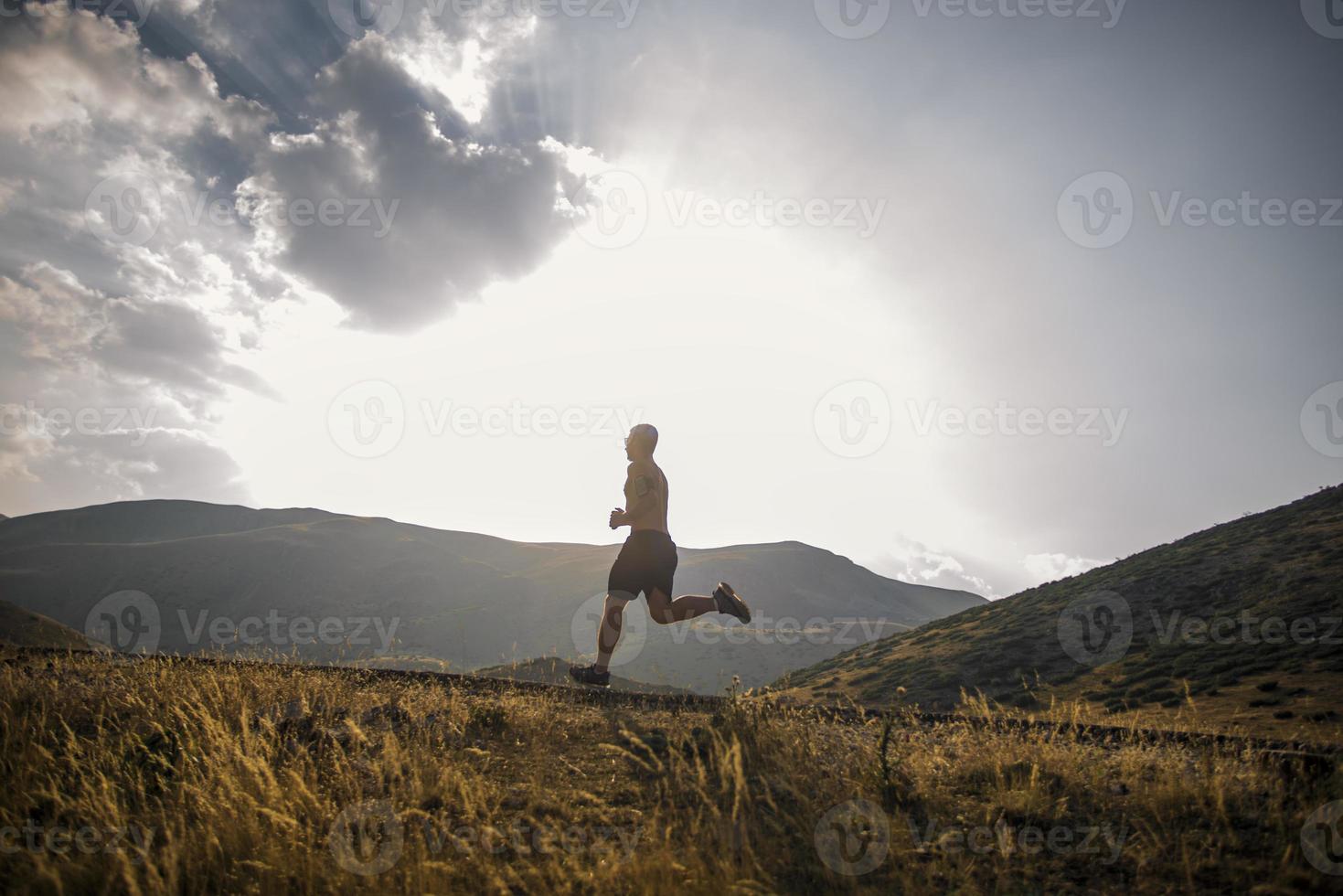 sporty man runner running on mountain plateau in summer photo