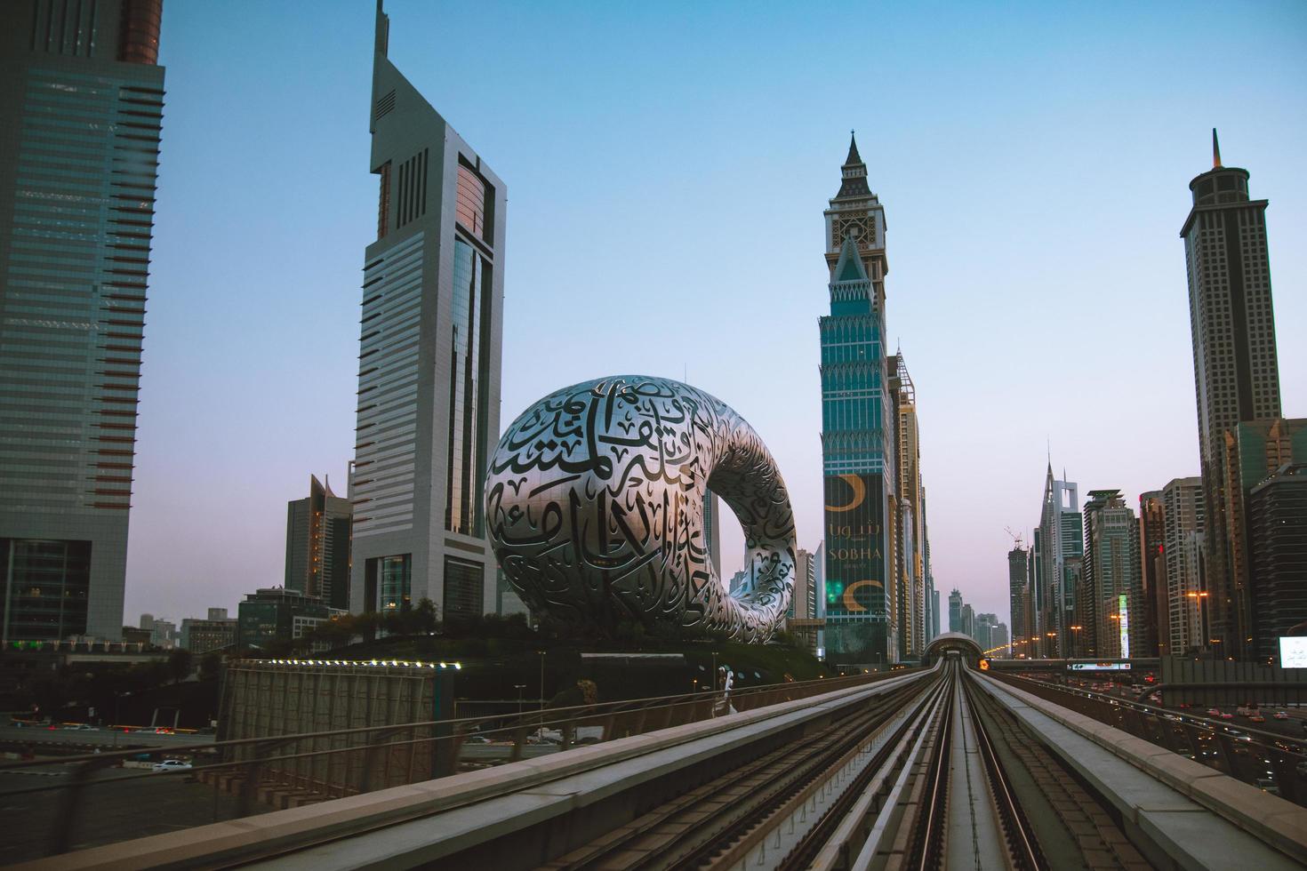Dubai, UAE , 2022 - metro train on railway in Dubai with museum of future and sunset sky background photo