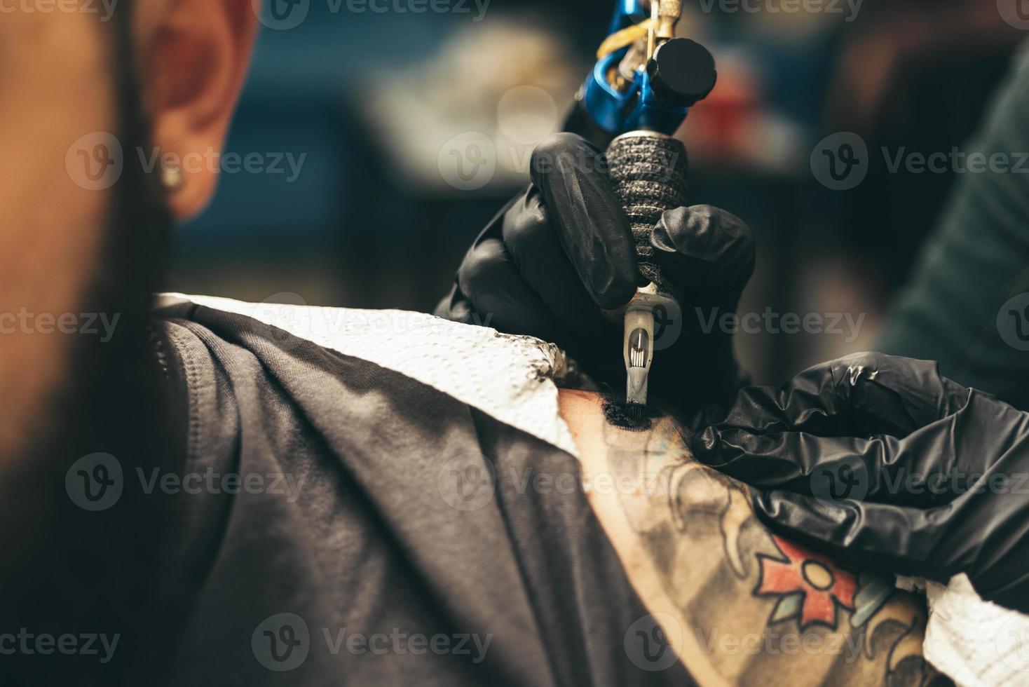 close up tattoo machine. Woman creating picture on hand with it in salon photo