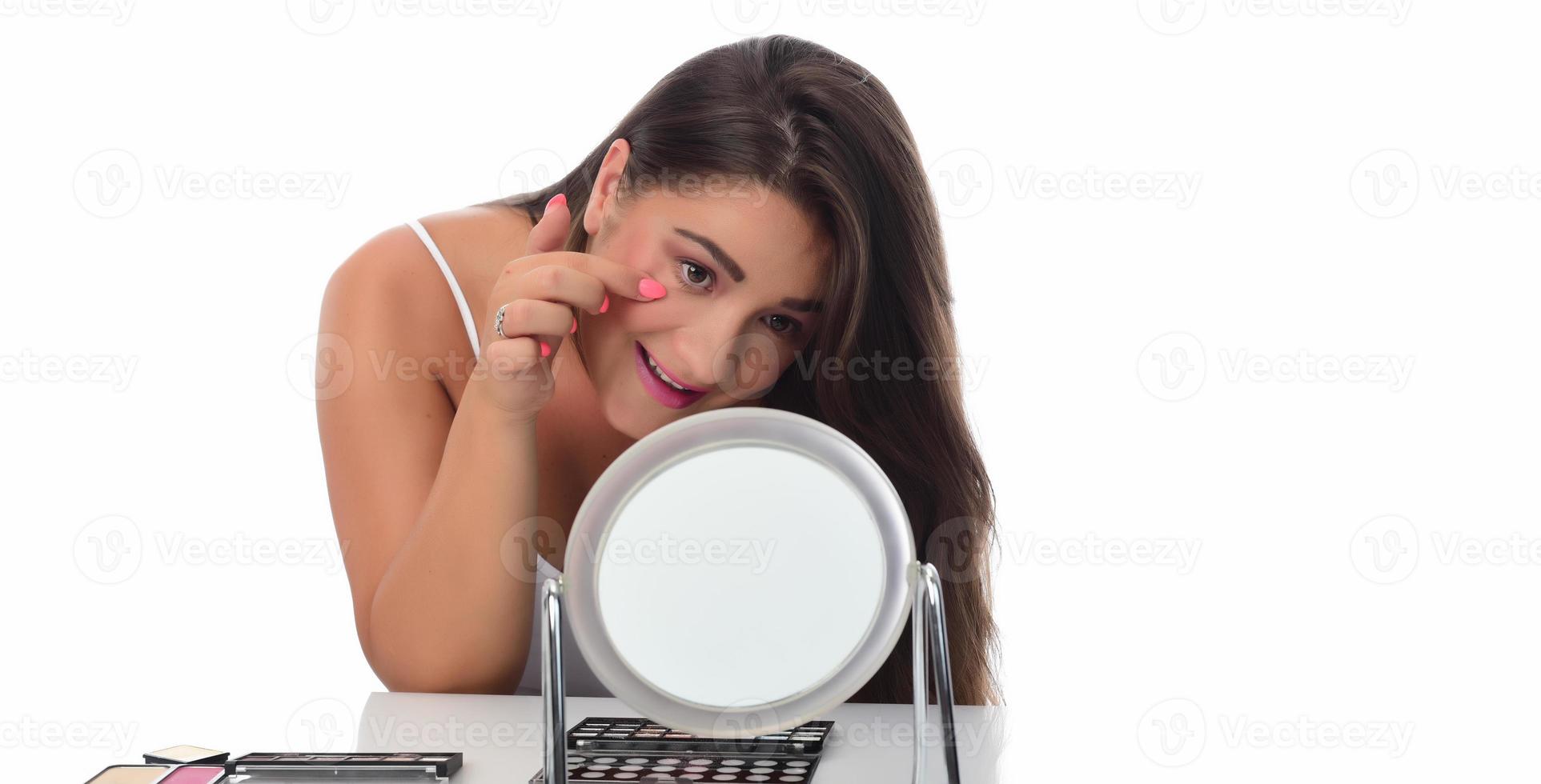 young woman checks her face skin in the mirror photo