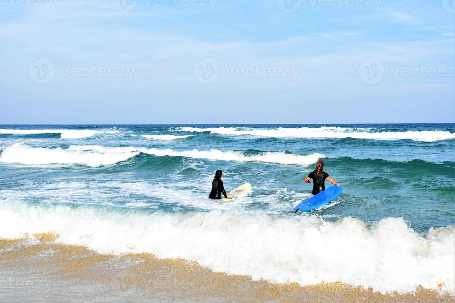 Surfers couple waiting for the high waves on beach - Sporty people with surf boards on the beach - Extreme sport and vacation concept photo