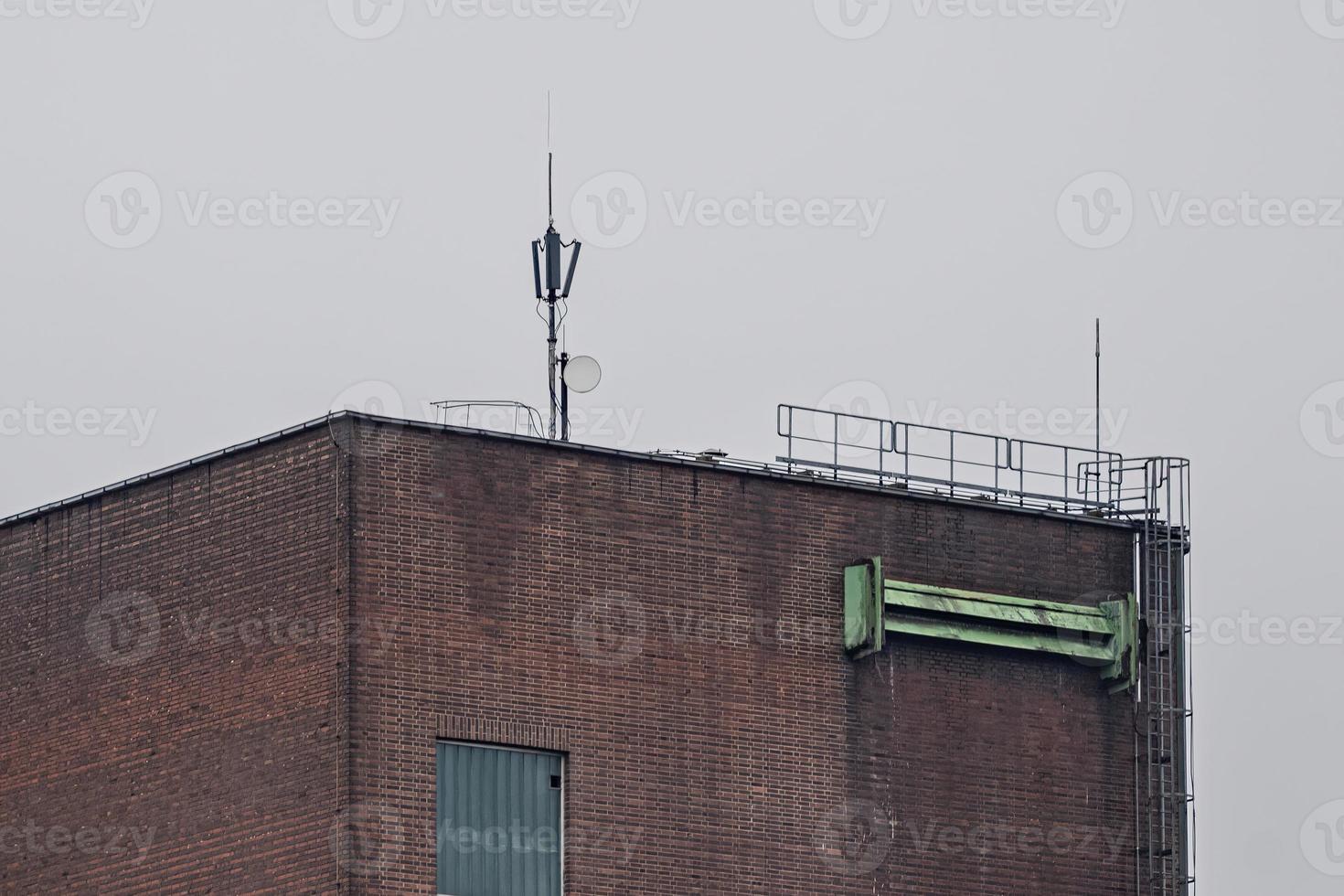 antenna on the roof of an brick industrial building photo