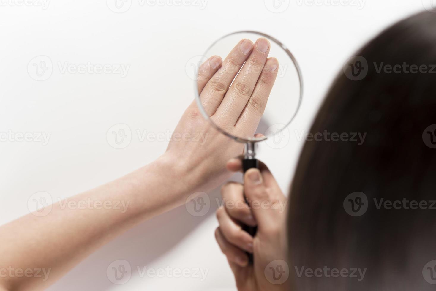 Woman looking her hand nails true magnifying glass. photo
