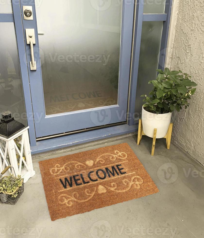 felpudo de entrada de bienvenida de diseñador colocado fuera de la puerta de entrada con planta y lámpara foto