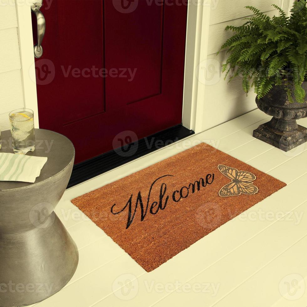 felpudo de entrada de bienvenida de diseñador colocado en el suelo fuera de la puerta de entrada con plantas y bebida de hielo de limón foto