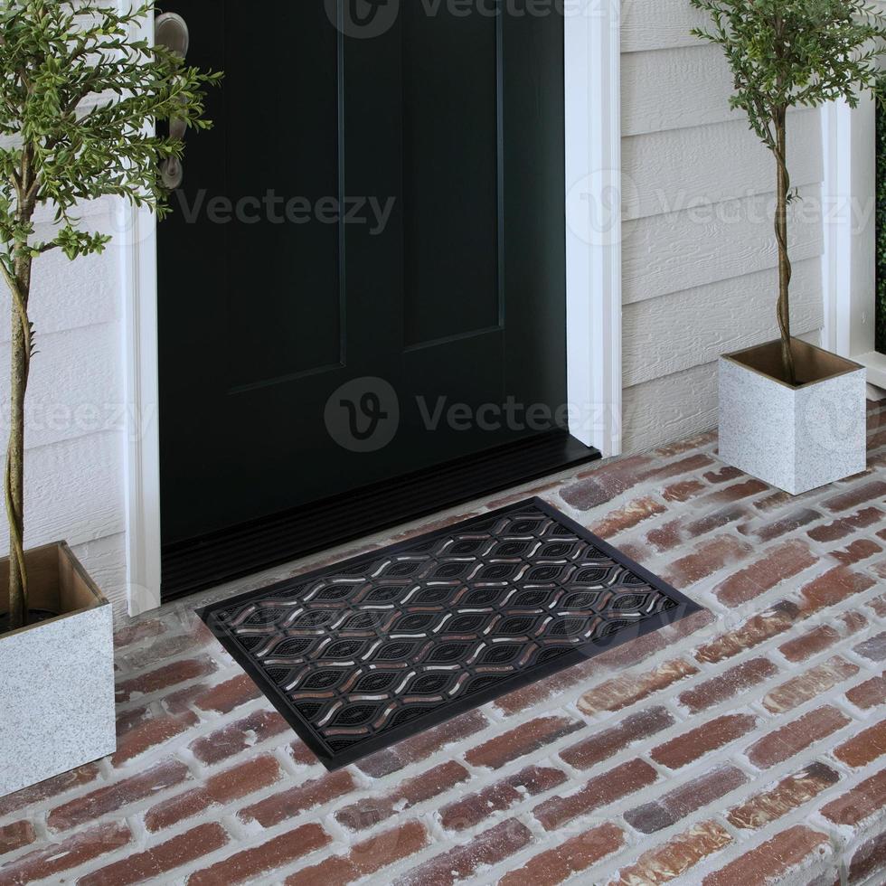 Designer Welcome Entry Doormat Placed on Solid Brick Floor Outside Entry Door with Plants photo